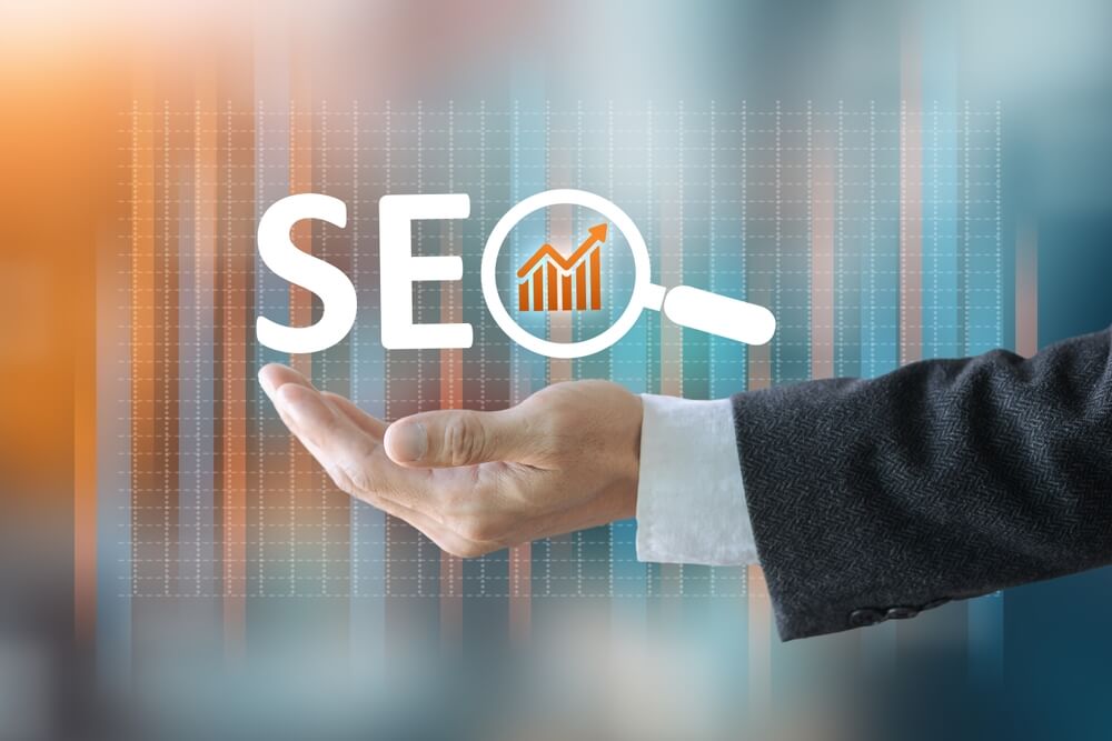 Hand holding SEO icon with magnifying glass and upward graph