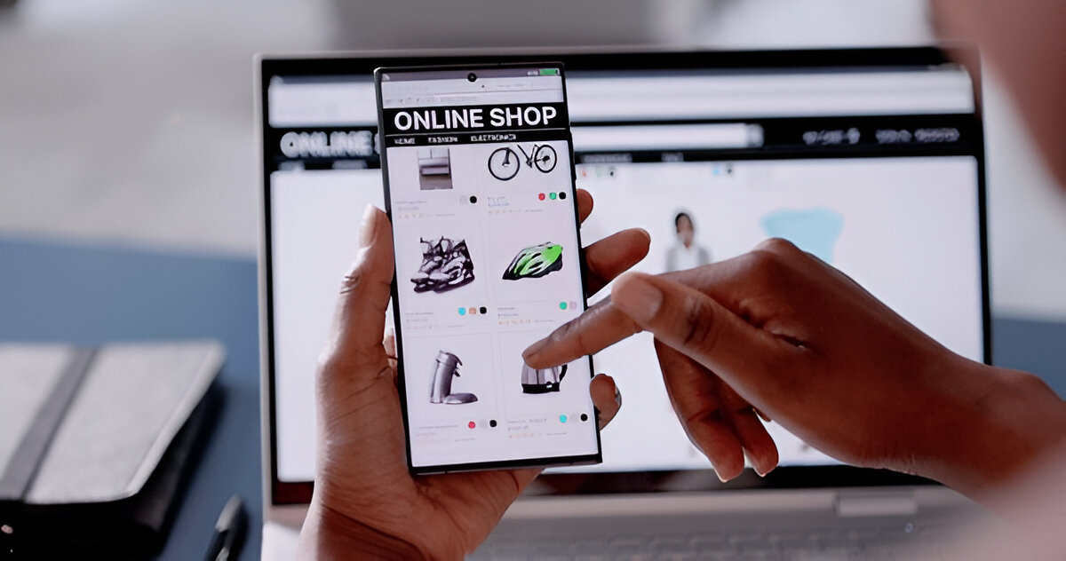 Person testing an online shop on a mobile device with a laptop in the background